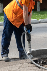 Dismantling of the road surface. A road worker with tension is hammering the asphalt with a...