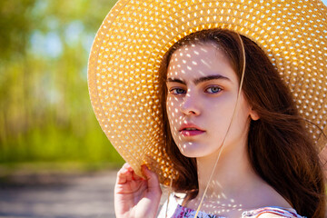 Portrait of a young beautiful girl in a straw hat