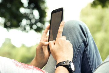der junge Mann im Gras auf der Sonnenbank liegen. Der Mann hat eine Tablette in der Hand.