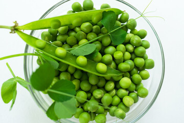 Green young peas in a plate. Top view. Close-up.
