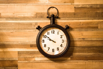 Old authentic clock hanging on a wooden wall.