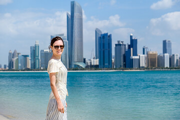 Beautiful young woman with sunglasses and Abhu Dhabi skyline