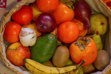 Close up of basquet full of fruits and a head of garlic.