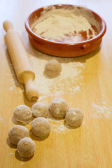 Balls of integral dough, wooden rolling pin and terracotta plate with flour.