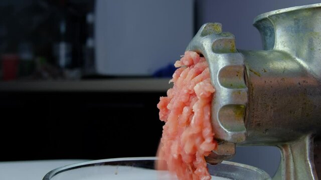 Cooking minced meat with a manual meat grinder. Close-up of front part of mincing-machine with mincemeat in. Showing the forcemeat process.