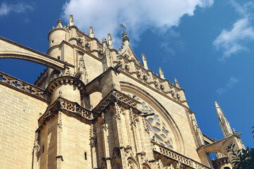 Fototapeta na wymiar Main gate of the gothic cathedral of Seville in Spain, with columns, buttress, arches and ornaments with a blue sky in the background