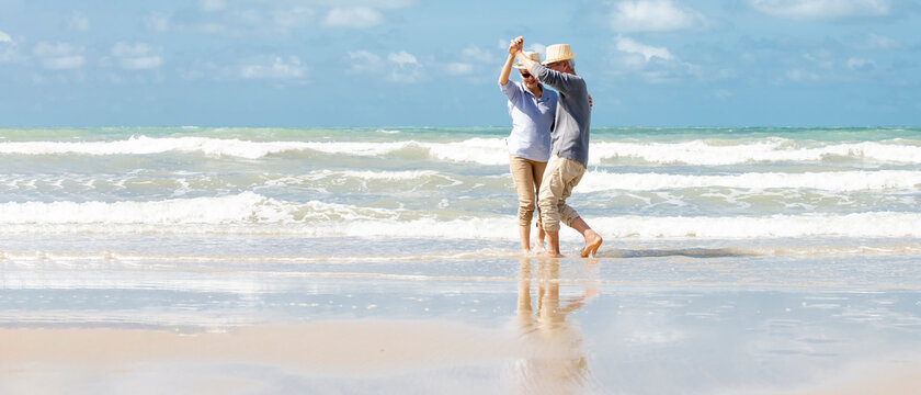 Happy  asian senior couple  dancing  on beach with blue sky background