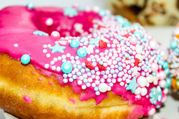 American doughnut close-up with pink icing and colored sprinkles. Diet concept.