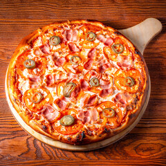 Delicious round pizza on a wooden stand on the table