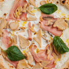 Italian pizza with mushrooms, basil and ham close-up.