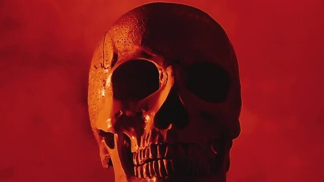 A scary human skull over a rising thick smoke, blood red color tones.
