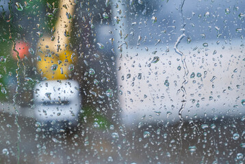 Raindrops on the window pane. A blurred silhouette of special equipment is visible from the window. Work to eliminate the accident does not stop during the rain. High quality photo