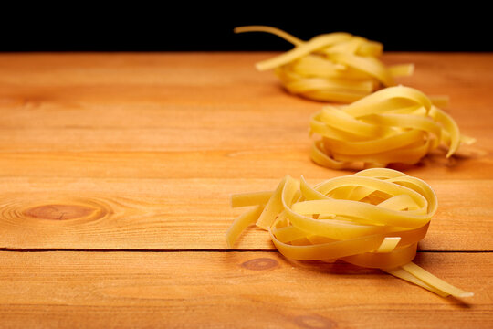 Raw uncooked pasta on the homemade wooden table, free space for text