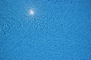 Top view of clear water in a blue tile pool background. Ripple effect