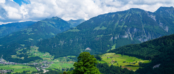 Panoramic view of idyllic scenery near Lake Lungern with fresh green meadows. Beautiful sunny day in springtime in Switzerland. Summer rural view. Village in green mountain valley.