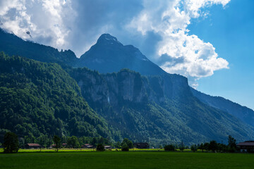 Fototapeta na wymiar Green fields and famous Lauterbrunnen valley with high cliffs in background, Oberland, Switzerland, Europe.