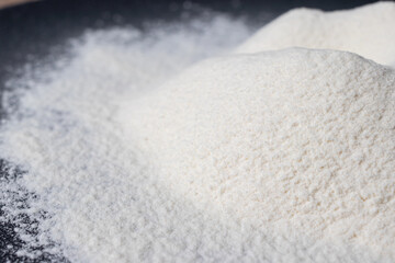 Wheat white flour on a black plate. Making bread and baked goods. Cooking at home