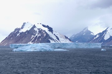 Iceberg before glacier wall and mountains, Antarctica