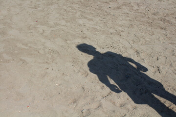 Shadow of man standing on sand background.