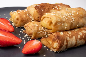 Wheat flour pancakes with strawberries and sesame. Sweet homemade pastries for breakfast.
