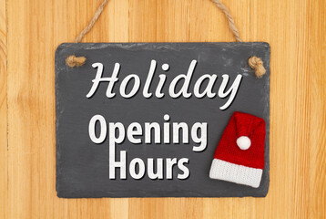 Holiday Opening Hours type message on hanging chalkboard sign with a Santa hat