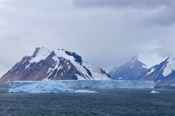 Iceberg before glacier wall and mountains, Antarctica