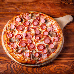 Delicious round pizza on a wooden stand on the table
