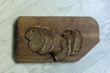 Homemade bread sliced ​​into pieces lies on a wooden board.