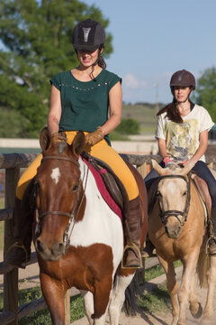 Sisters with happy actitude at a horse riding lesson.