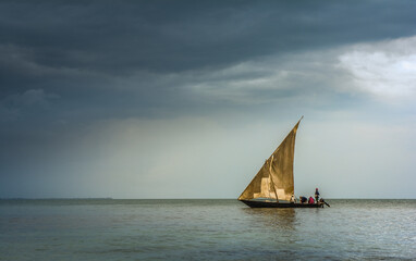 Fototapeta premium Dhowboat sailing into rainstorm off the coast of Tanzania, locals fishing
