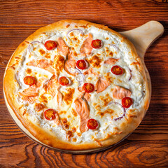 Delicious round pizza on a wooden stand on the table