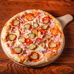 Delicious round pizza on a wooden stand on the table
