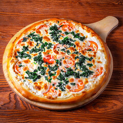 Delicious round pizza on a wooden stand on the table