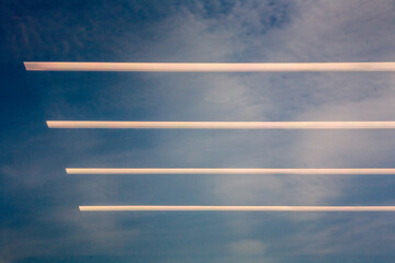 Reflection of fluorescent lighting tubes in window against blue sky