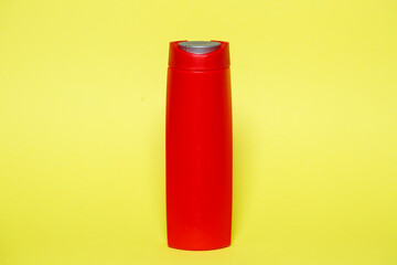 Red bottle with gel shampoo or liquid soap on a yellow background