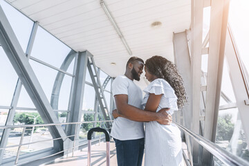 Fototapeta premium African american couple in love cuddling in airport corridor
