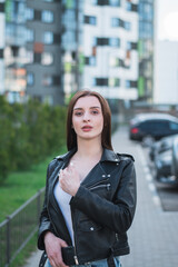 Fototapeta na wymiar beautiful stylish young girl in a black leather jacket on the streets