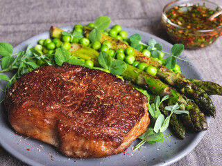 juicy roasted beef chopped steak, with green peas, asparagus, on plate close up, sauce
