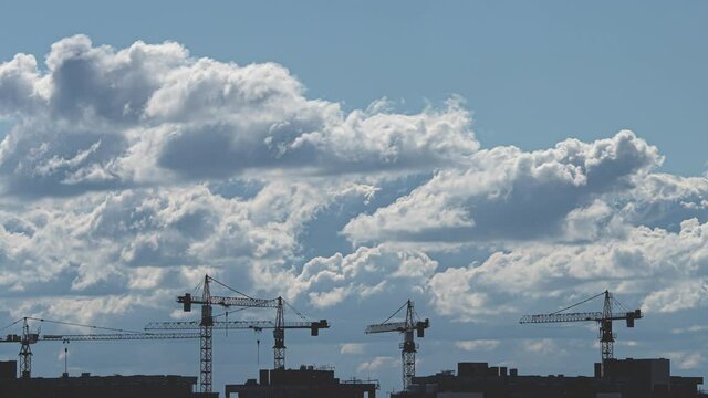 The stream of clouds over the building cranes. time lapse