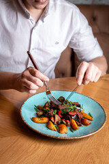roast meat with potatoes on a plate, hand with a fork