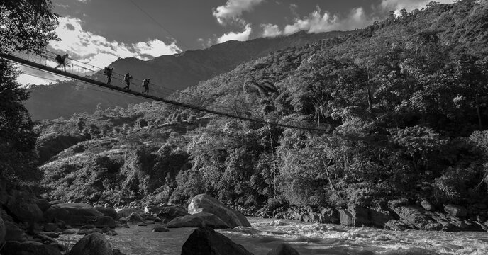 A group of trekkers crossing the suspension bridge ove Marshyangdi river and their way to Bhulbhule village and Besi Sahar village, Nepal, Nepal Himalayas.