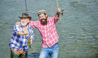 male friendship. family bonding. summer weekend. Coming together is a beginning. men fisher. father and son fishing. hobby and sport activity. Trout bait. two happy fisherman with fishing rod and net