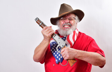 Fierce old man, armed with a sawed off rifle, wearing patriotic colors, eyeglasses and a floppy western hat.. - obrazy, fototapety, plakaty