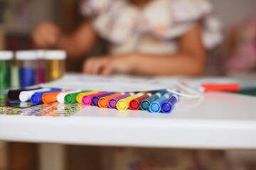 Fototapeta premium Boys' markers on a girl's bokeh table. Selective focus