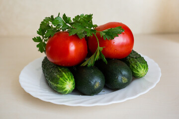 A fresh tomatoes, sliced cucumbers and sprig of parsley on the white plate on the light table. Seasoning vegetables on a table. Healthy ingredient for salad.