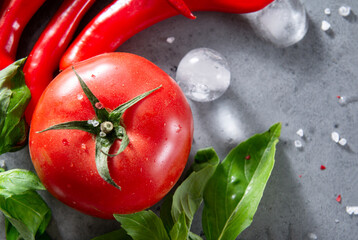 several red chili peppers, green Basil sprigs, ice cubes ,1  red tomato,  salt, spices  on a gray