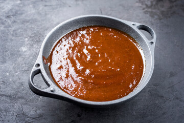 Hot and spicy barbecue sauce offered as overhead view in a modern design bowl with copy space