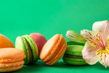 peach, green macaroon cookies with  Alstroemeria flower on a green background