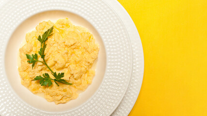 scramble omelette in a white plate on a yellow background