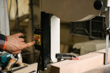 a man sawing a wooden board on a band saw,close up